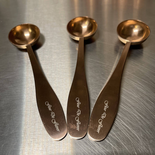 Set of three Fleur De Flavor Rose Gold Teaspoons with engraved handles, ideal for precise baking measurements and elegant kitchen presentation.